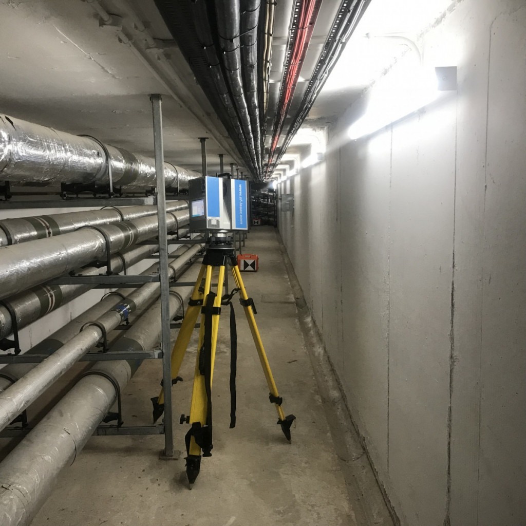 3D scanner on tripod inside an undergrouind concrete culvet with service pipes and cables running through it