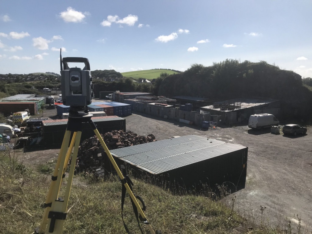 Total Station on cliff overlooking a disused quarry full of shipping containers