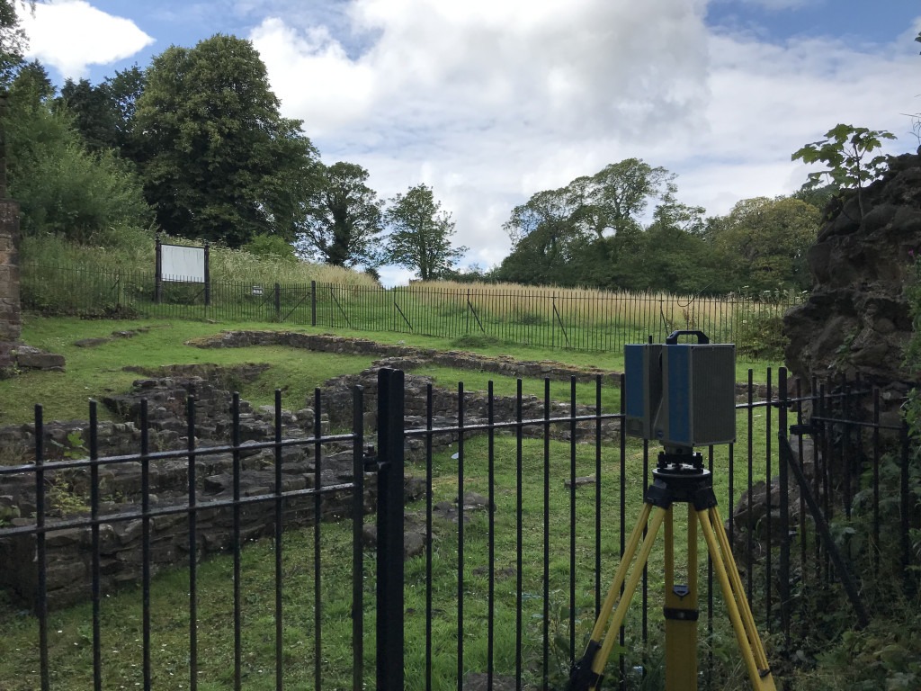 Fenced stone wall ruin with a 3D scanner on Yellow tripod outside the gate.