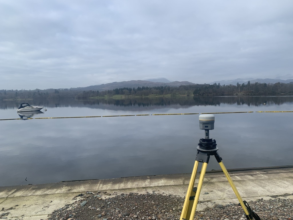 GNSS Receiver measuring a control point on the shore of Lake Windermere as a boat passes by